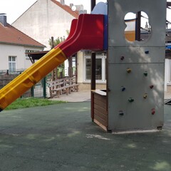 Des plaques amortissantes contre les chutes de WARCO en vert gazon ont été installées sous la tour de jeux avec un toboggan, un mur d’escalade et un pont suspendu pour les enfants.