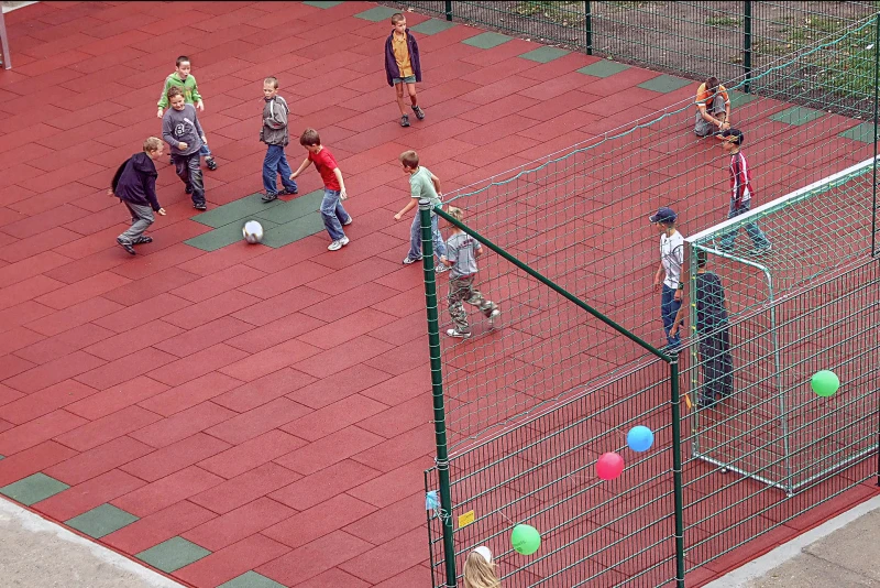 Zicht van boven op een voetbalveld of een klein speelveld gemaakt van balpanelen van WARCO. Een groep kinderen is aan het voetballen.