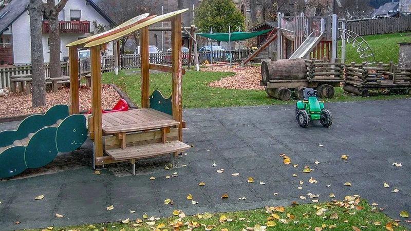 Une grande aire de jeux naturelle à Olsberg faite de dalles antichoc WARCO vertes avec une petite maison de jeu en bois.