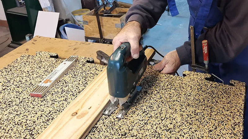 Op de foto wordt een WARCO-vloertegel in puzzelvorm met een decoupeerzaag bewerkt. Het flexibele materiaal is eenvoudig te bewerken met gangbaar gereedschap, zodat een exacte pasvorm mogelijk is. Zo kan de vloerbedekking perfect worden aangepast aan randen, hoeken en uitsparingen. De robuuste en elastische toplaag blijft onbeschadigd, wat een duurzame en onderhoudsvriendelijke oplossing garandeert.
