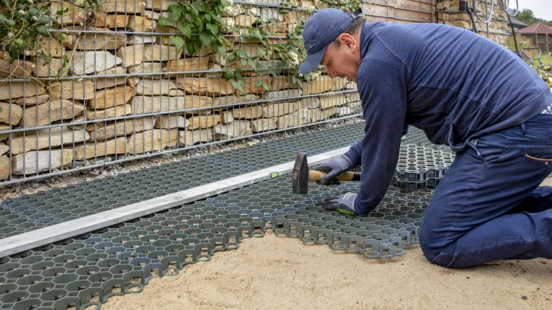 Kunststoff-Wabengitter, Rasengitter oder Parkplatzgitter eignen sich nicht nur als wasserdurchlässige Befestigung für einem Parkplatz oder einer Zufahrt, sondern auch als Tragschicht für Bodenbeläge von WARCO. Hier werden die Parkplatzgitter in einer Bettung aus Splitt und Sand verlegt.