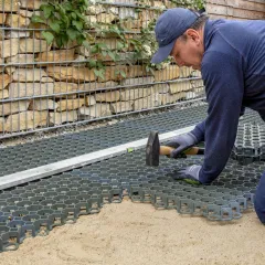 Kunststoff-Wabengitter, Rasengitter oder Parkplatzgitter eignen sich nicht nur als wasserdurchlässige Befestigung für einem Parkplatz oder einer Zufahrt, sondern auch als Tragschicht für Bodenbeläge von WARCO. Hier werden die Parkplatzgitter in einer Bettung aus Splitt und Sand verlegt.