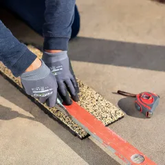 Mit entschiedenen, schnellen Bewegungen, bei denen das Messer an einer Schiene entlang geführt und bei jedem Schnitt immer etwas weiter in die Platte eindringt, kann man bei Gummigranulat-Platten ganz einfach gerade und saubere Schnitte ausführen.