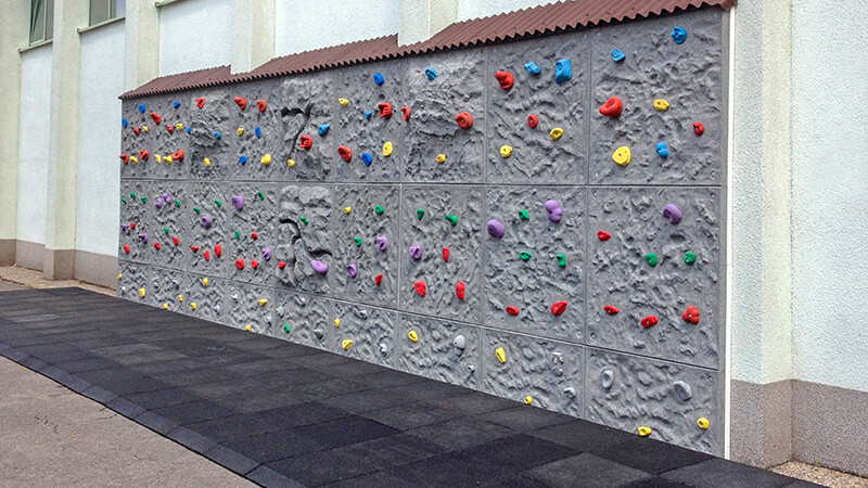 Un espace devant le mur escalade est recouvert de dalles de protection antichute WARCO noirs en granulat de caoutchouc.