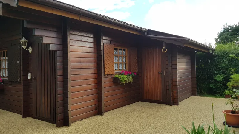 Le carrelage terrasse WARCO en tonalité Travertin constitue l’entourage de la maison de vacances en bois.