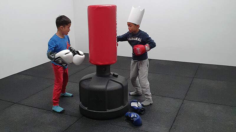 Deux enfants boxent sur un sac de frappe, le 
revêtement pour salle de sport WARCO en couleur Anthracite offre une bonne protection contre les chutes.