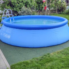 Dans le jardin, une piscine gonflable est installée sur le sous-plancher antidérapant pour piscine WARCO en couleur vert gazon.
