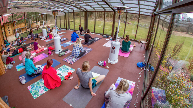 La salle de yoga avec des tapis sportifs WARCO en rouge brique, où de nombreux praticiens en yoga font leurs exercices.