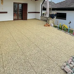 Sur une terrasse partiellement couverte, des dalles de terrasse WARCO en granules de caoutchouc liés au PU affichent une teinte beige chaleureuse évoquant le travertin naturel. Antidérapantes, amortissantes et faciles d’entretien, elles conviennent parfaitement à l’extérieur. Leur structure poreuse favorise l’évacuation rapide de l’eau de pluie, tandis que la surface élastique protège du froid du sol. Sans collage permanent, elles offrent une grande liberté d’aménagement. Le résultat est un espace extérieur confortable à l’ambiance accueillante.
