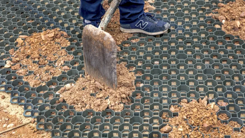 Die eben ausgelegten Rasengitter, Parkplatzgitter oder Kunststoff-Wabengitter werden mit einem Gemisch aus Splitt und Sand sorgfältig aufgefüllt. Die Gitterwaben müssen komplett befüllt werden. Dabei darf das Material nicht zu grobkörnig und nicht zu feinkörnig sein, denn die fertige Fläche soll gut wasserdurchlässig bleiben.