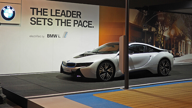 La voiture i8 de BMW est présentée lors d'un salon. La super voiture de sport est posée sur le sol noir de WARCO, qui reproduit l'asphalte d'une route.