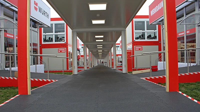 Een overdekt pad leidt naar de afzonderlijke themagebieden op de Würth Informatiedagen 2019. Alle vloeroppervlakken zijn bedekt met de zwarte kliktegel voor beursvloeren.