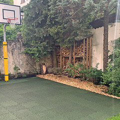 Le nouveau terrain de basket avec un revêtement de sol sportif en caoutchouc vert de WARCO, réalisé dans la cour d'un immeuble d'habitation.