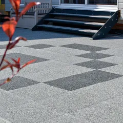 Sur une vaste terrasse, des dalles de terrasse WARCO en granules de caoutchouc liés au PU sont posées en joints croisés, formant un damier saisissant. Les dalles gris clair sont ponctuées de quelques dalles gris foncé dessinant une figure géométrique. Ce revêtement élastique est antidérapant, facile d’entretien et atténue les bruits de pas. De plus, il résiste aux intempéries et convient à un usage toute l’année, apportant davantage de confort en extérieur.