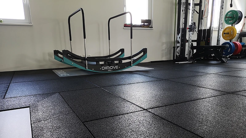 Fitnessapparatuur zoals halters, rugtrainer en wip staan op zwarte Warco-platen. Wiggen vergemakkelijken de overgang.