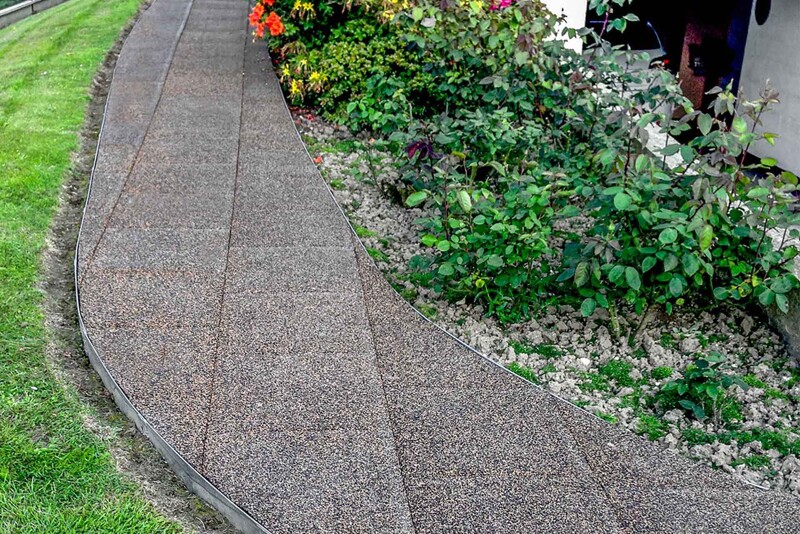 Les dalles carrées en caoutchouc WARCO peuvent également être utilisées pour créer un chemin courbé dans le jardin.