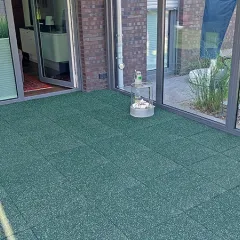 Sur la terrasse se trouve un revêtement en dalles WARCO de couleur verte. Ces dalles maniables sont posées avec un joint croisé classique et maintenues ensemble par un emboîtement caché. Le granulat de caoutchouc offre une surface antidérapante, facile d’entretien et isolante contre le froid du sol, prolongeant ainsi la saison de la terrasse.