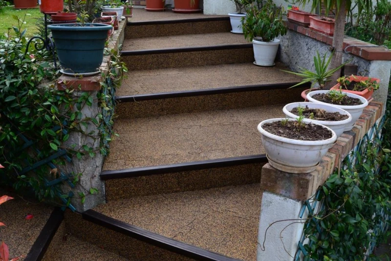 Un escalier extérieur fait de dalles antidérapantes et sûres en couleur brune appelé Café au lait de WARCO monte au jardin.