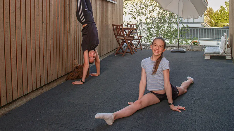 [Ausführliche Bildbeschreibung]
Sur une terrasse est installé un revêtement WARCO anthracite en granules de caoutchouc liés au PU. Deux filles pratiquent la gymnastique sans contrainte, profitant de la surface élastique, amortissante et antidérapante. La structure poreuse accélère le séchage, tandis que l’emboîtement puzzle autorise une pose flexible sans colle. Ce matériau robuste et facile d’entretien convient parfaitement à une vie active.